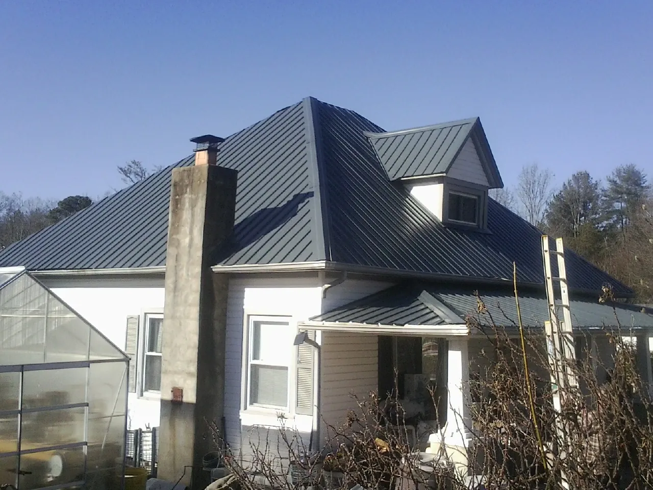 Dark blue standing seam metal roof on a white farmhouse with dormer — Slate & Tile Roof Repair by Roofing Brothers in Loa
