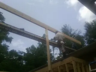 Carpenter setting a ridge beam over a new addition frame — Ice Dam Removal by Roofing Brothers in Loa