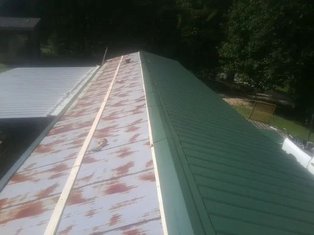 Old rusted panels beside newly installed green metal roofing — Wind Damage Roof Repair by Roofing Brothers in Loa