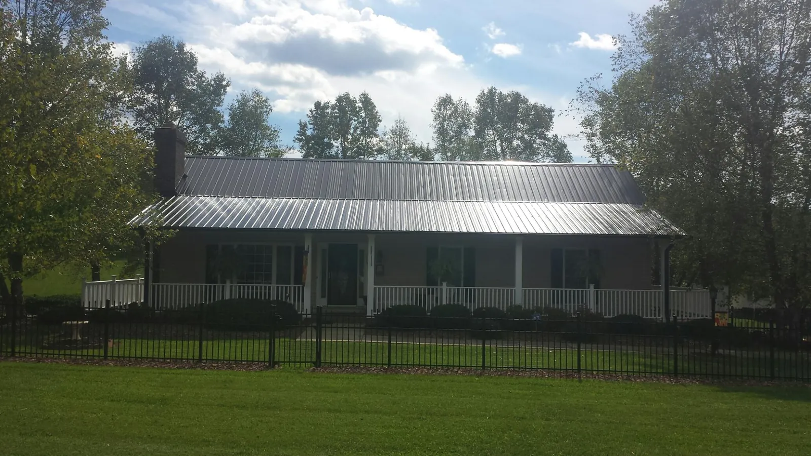 Gray metal roof on a brick ranch with a full width front porch — Gutter Guard Installation work by our crew in Loa